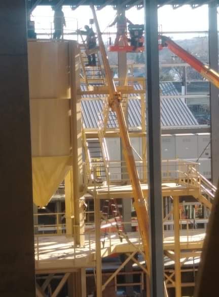 Yellow steel access stairway and platform installed alongside a bond silo